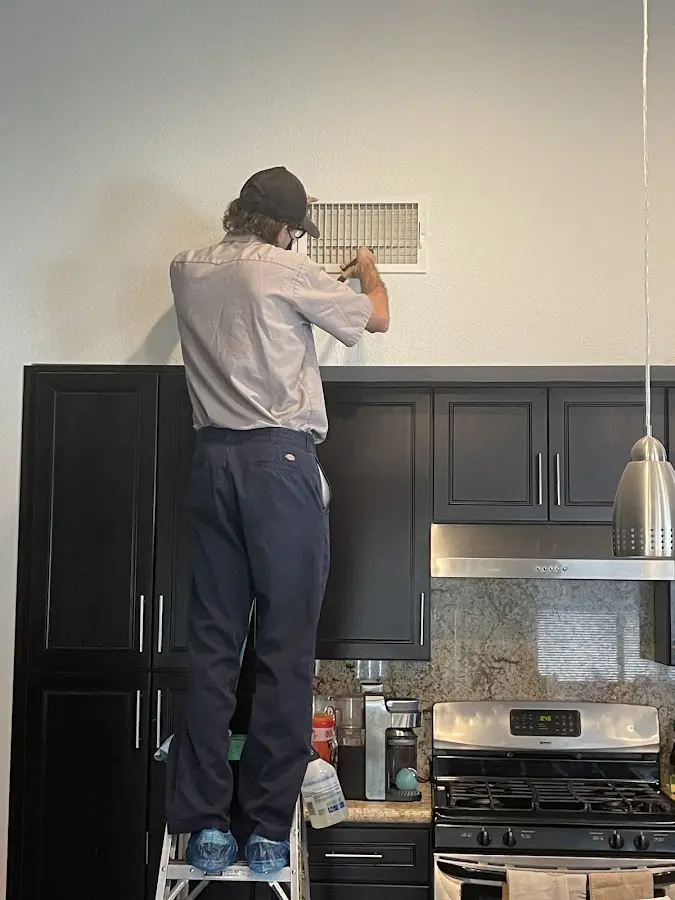 Technician inspecting an air vent during HVAC service in Sullivan